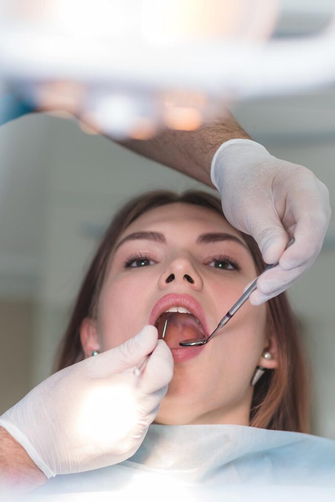 A dentist performing a routine oral exam using a mirror and explorer for a patient at our Pittsfield Charter Twp location.
